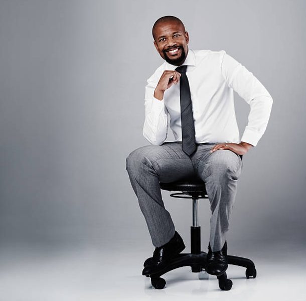 Studio portrait of a corporate businessman sitting on a chair against a grey background